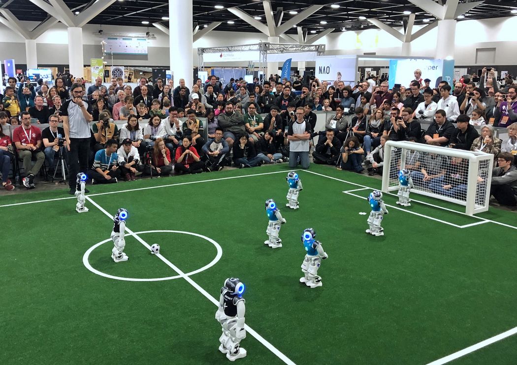 B-Human Roboteam auf dem Feld im Finale, Ziellinie bis Tor, im Hintergrund volle Publikumsränge