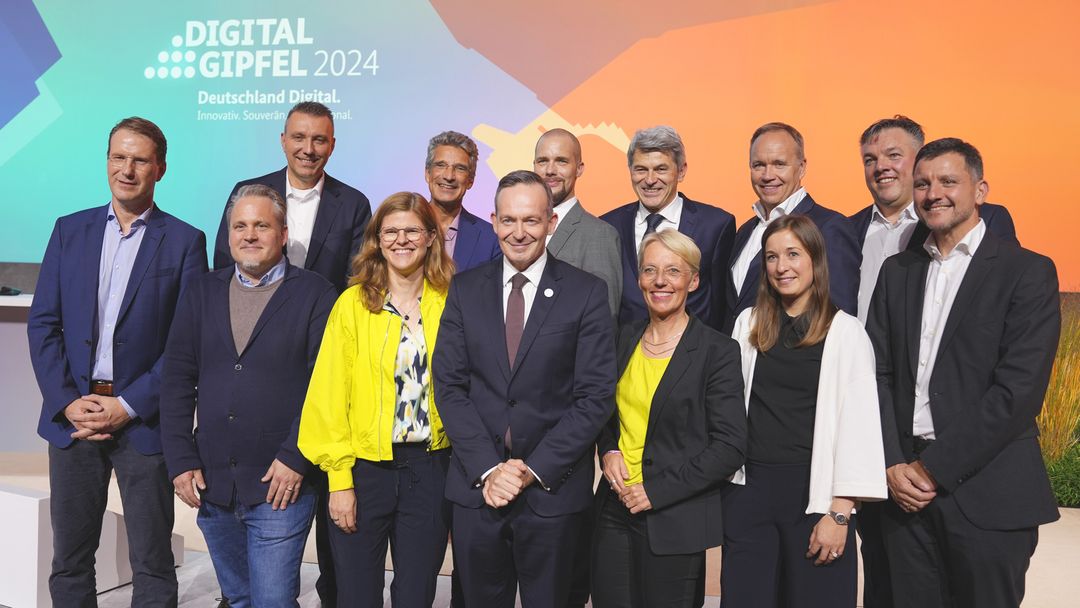 Ein Gruppenfoto von allen beteiligten Projekt-Partners mit Bundesdigitalminister Wissing. Sie stehen auf der Bühne des Digital-Gipfels 2024. 