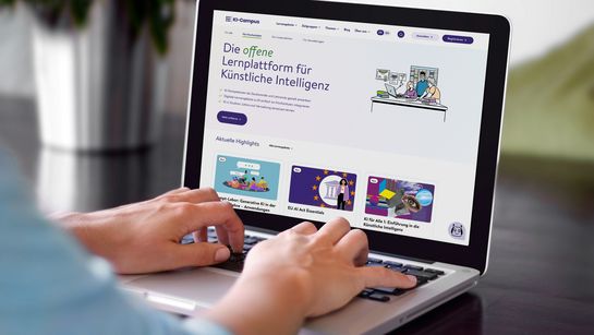Das Bild zeigt eine Person, die an einem Laptop arbeitet. Man erkennt nicht, welches Geschlecht diese Person hat. Auf dem Laptop sieht man die KI-Campus Lernplattform. Auf der Plattform steht: Die offene Lernplattform für Künstliche Intelligenz. Man sieht außerdem ein paar der Kursangebote der Plattform,einer davon heißt 